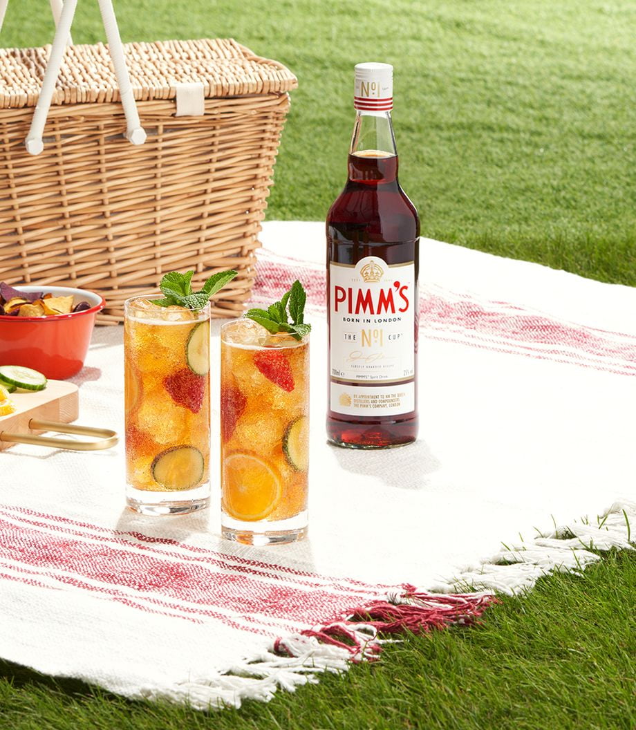 Pimms No.1 bottle and a batch of drinks topped with fruit