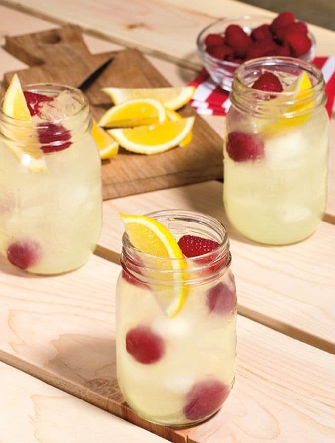 Summery cocktails with lemon slices and berries on a picnic table