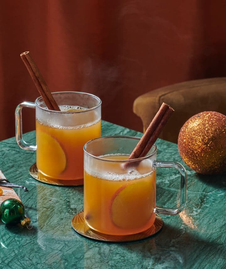 Dos vasos de whisky con canela y naranja.