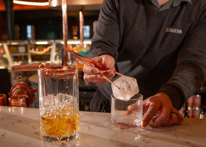 El bartender sirve un whisky en las rocas.