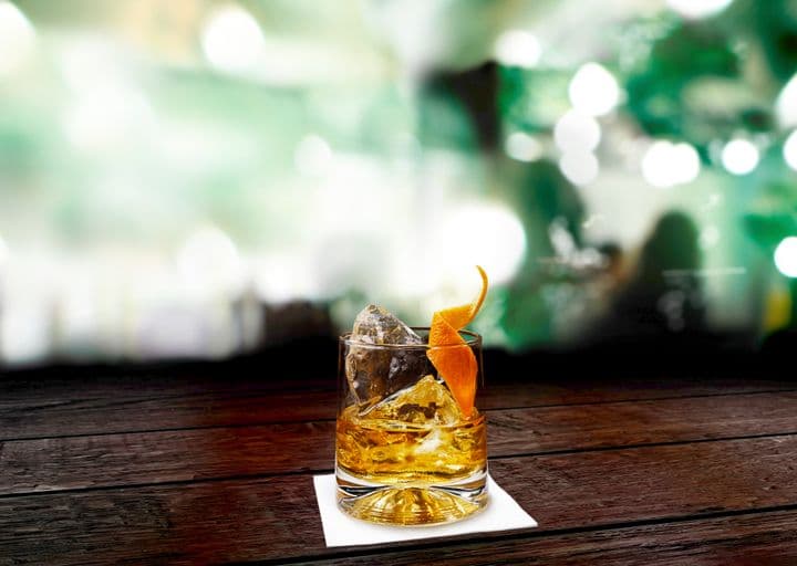Whisky en las rocas con cascara de naranja como decoración.