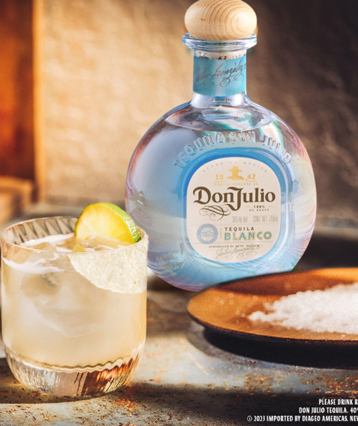 En la imagen se ve la botella de Don Julio Blanco, un plato con sal gruesa delante y un vaso con el trago, decorado con una rodaja de limonada