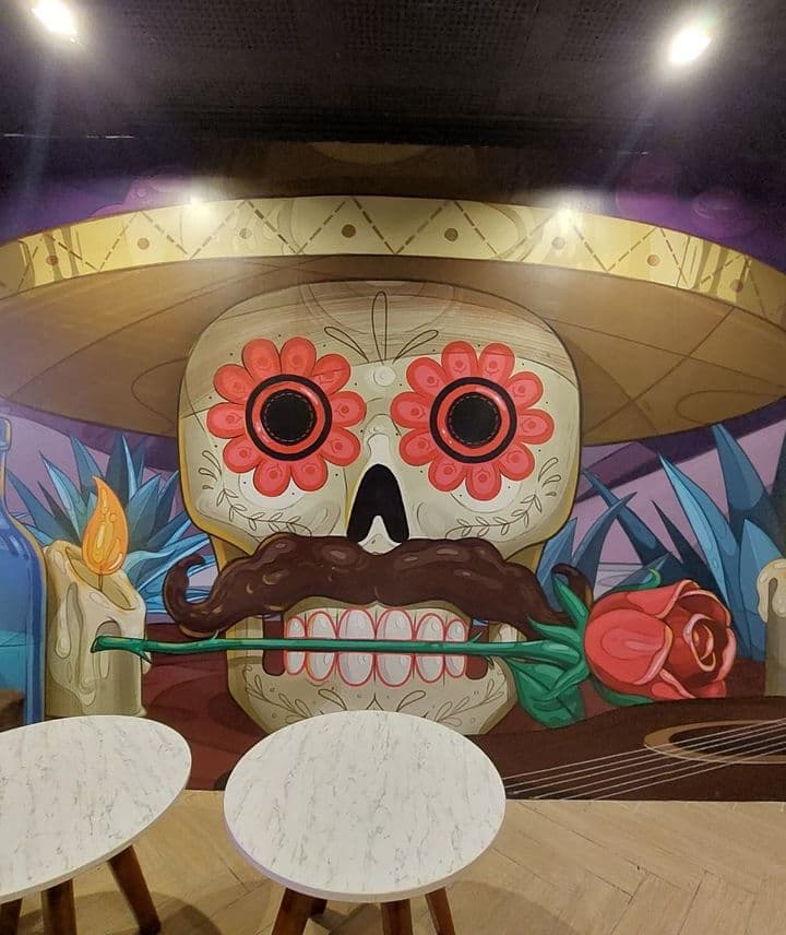 En la imagen se ve un mural del estilo mexicano que se encuentra como decoración en el bar Rosa Mezcal.