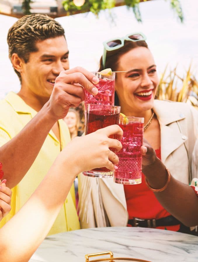La imagen muestra cuatro personas brindando con vasos que contienen cócteles preparados con vodka Smirnoff.