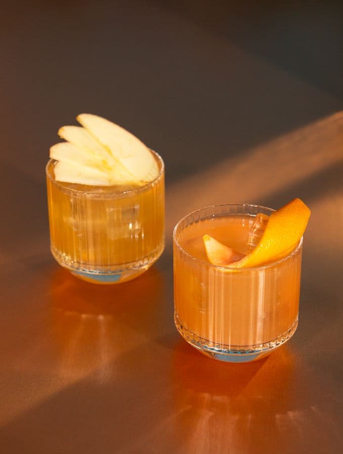 Dos vasos de whisky con cáscara de naranja