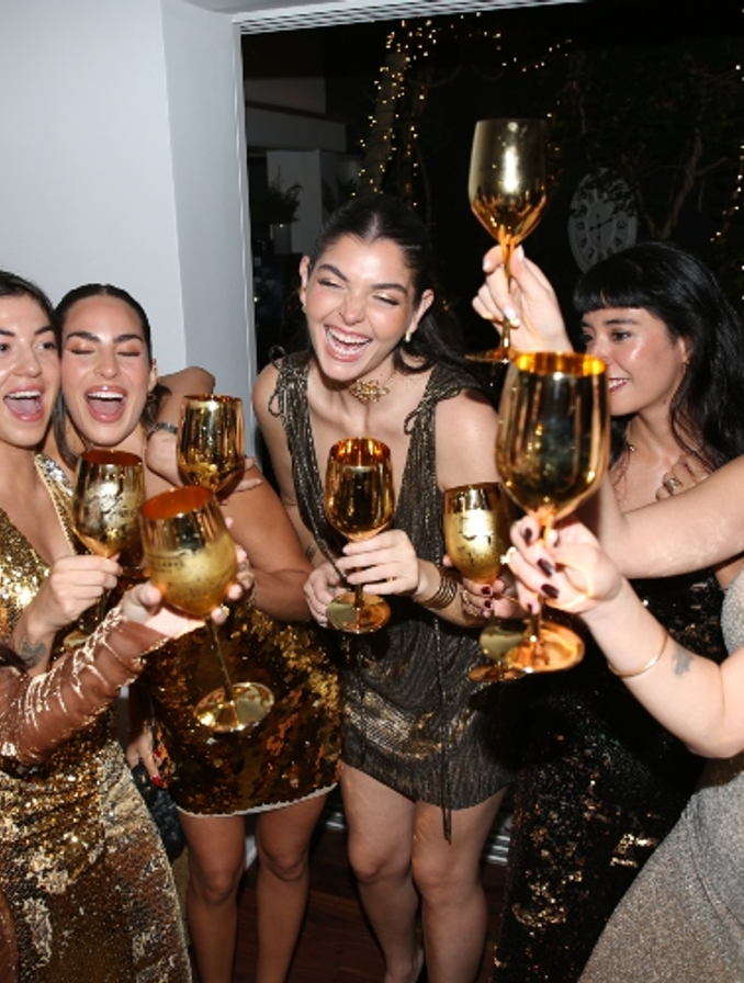 En la imagen se aprecia un grupo de chicas con vestidos dorados agarrando una copa dorada con Johnnie Walker Gold Label Reserve