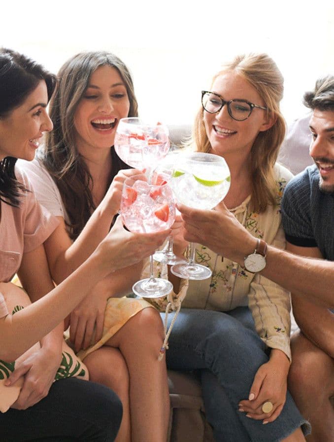 La imagen muestra a un grupo de amigos, cada uno con una copa con cóctel en la mano.
